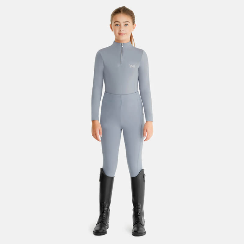 Young girl in Aztec Diamond YR Baselayer Ash Blue and black tall boots, facing forward.