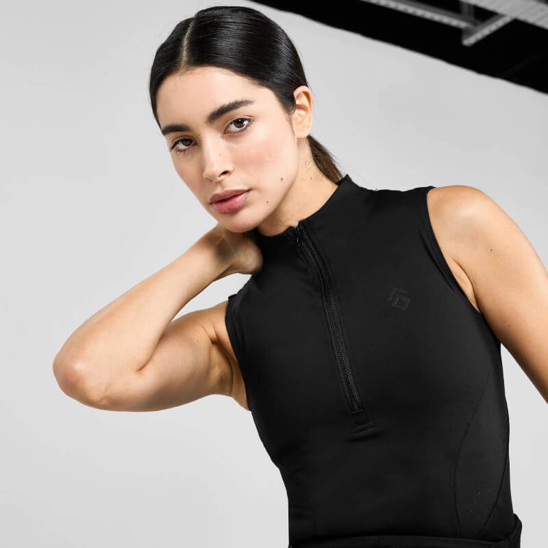 A woman wears the Aztec Diamond Core Sleeveless Baselayer Black against a plain, light background.