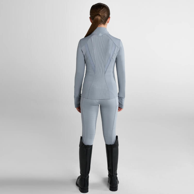 Young person in Aztec Diamond YR Fitted Jacket Ash Blue and black riding boots stands poised.