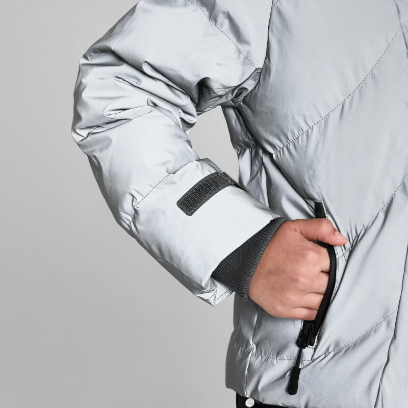 Model in Aztec Diamond YR Reflective Puffer Coat with hand in pocket, set on gray backdrop.