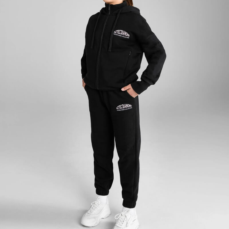 Model in Aztec Diamond YR Sweatpants Black/Pink stands against a gray background.