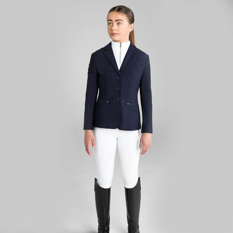 Young woman wears Aztec Diamond YR Competition Jacket Navy and white pants against gray background.