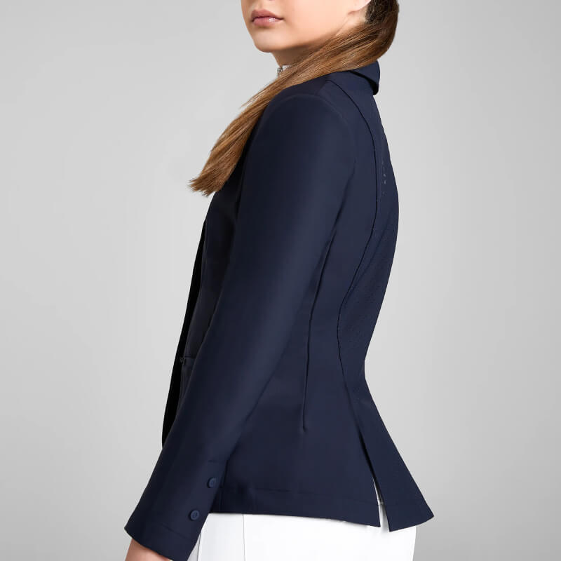 Woman wears Aztec Diamond YR Competition Jacket Navy and white pants, side view on gray background.