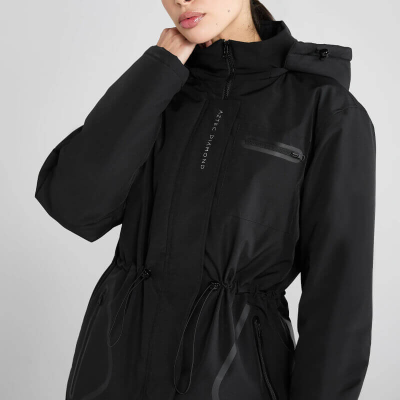 Woman wears Aztec Diamond Black Fleece Lined Rain Jacket with zippered pockets, neutral backdrop.