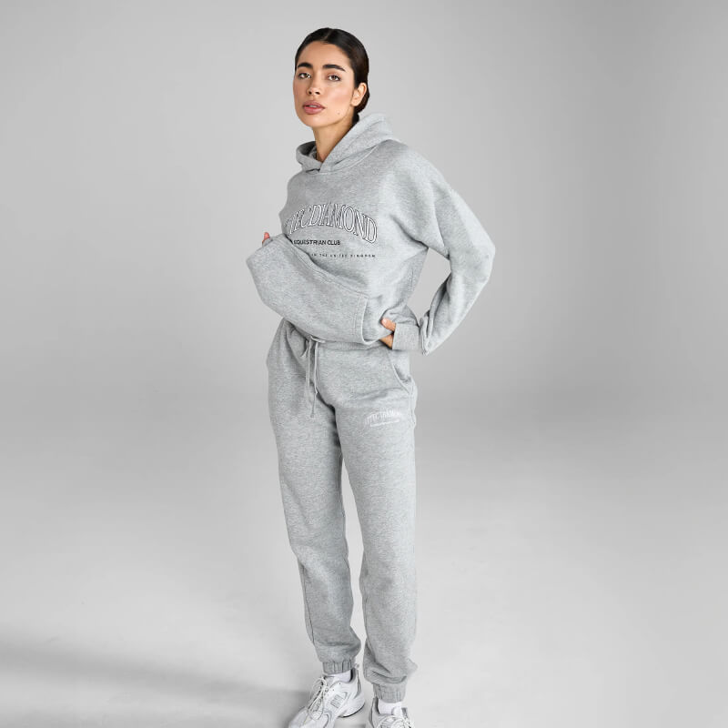 Woman in Aztec Diamond EQ Club Pull On Hoodie Grey Marl, sitting indoors.