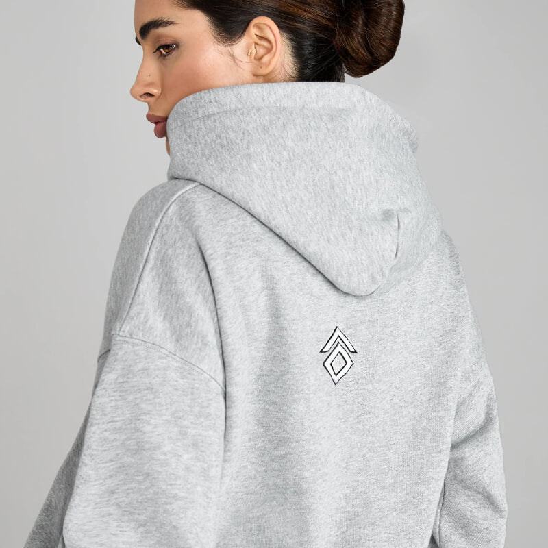 Woman in an Aztec Diamond EQ Club Pull on Hoodie Grey Marl with a geometric back logo, sideways.