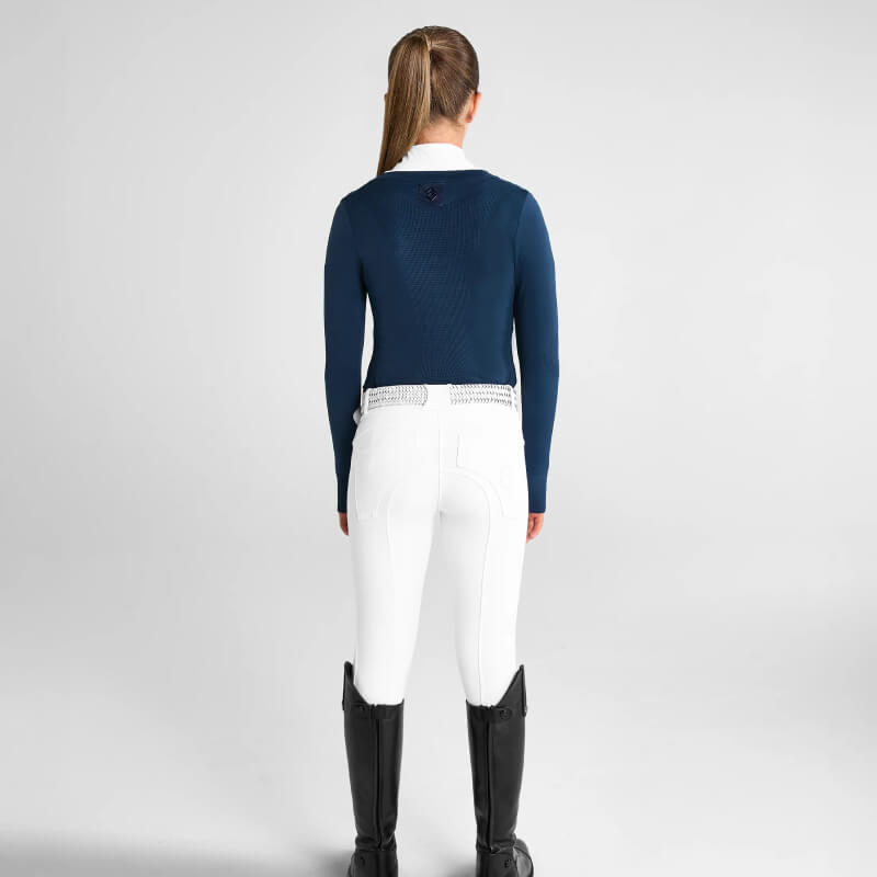Woman in white pants, black boots, wearing Aztec Diamond YR Show Sweater Navy from the back.