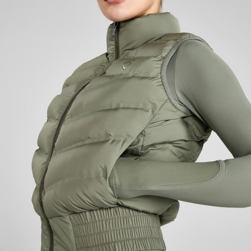 Woman in Aztec Diamond Lightweight Gilet Sage stands against a gray background.