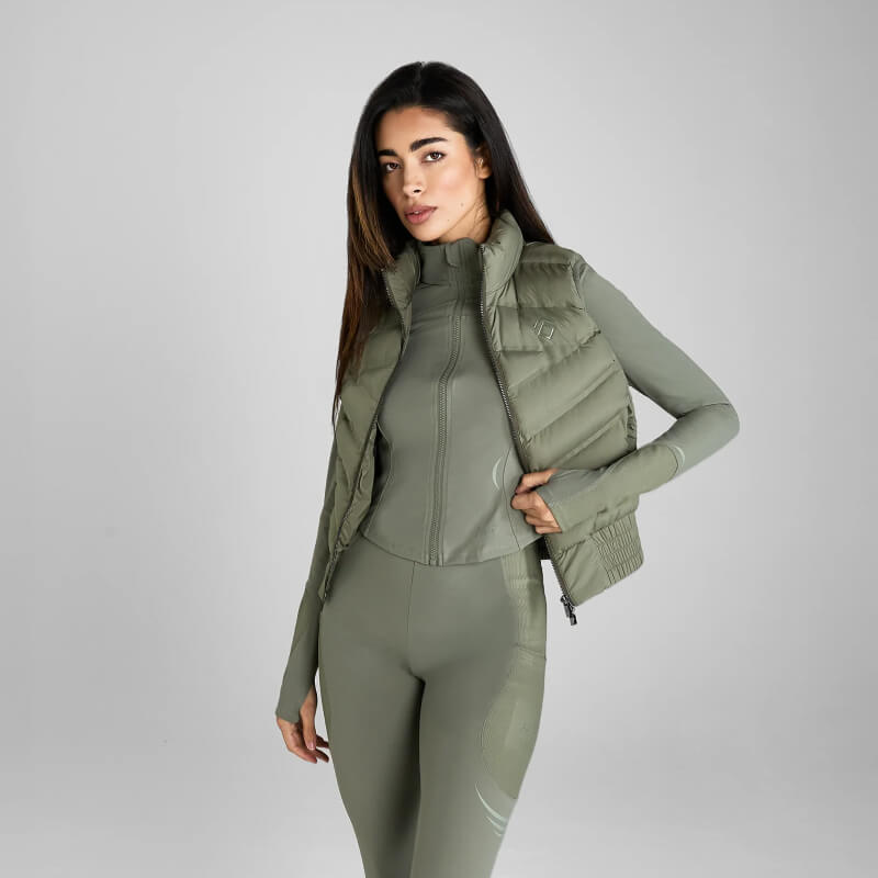Woman in Aztec Diamond Lightweight Gilet Sage poses against a plain gray background.
