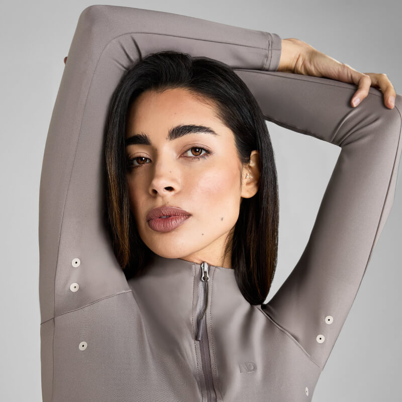 Woman with straight dark hair wears Aztec Diamond Define Baselayer Truffle zip-up top.