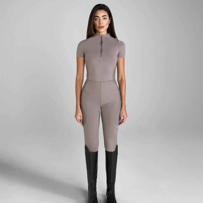 Woman wears Aztec Diamond Define Leggings Knee Grip Truffle and tall black boots in gray setting.