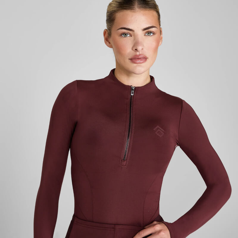 Woman wearing Aztec Diamond Core Baselayer Cherry, posing with one hand on her hip.