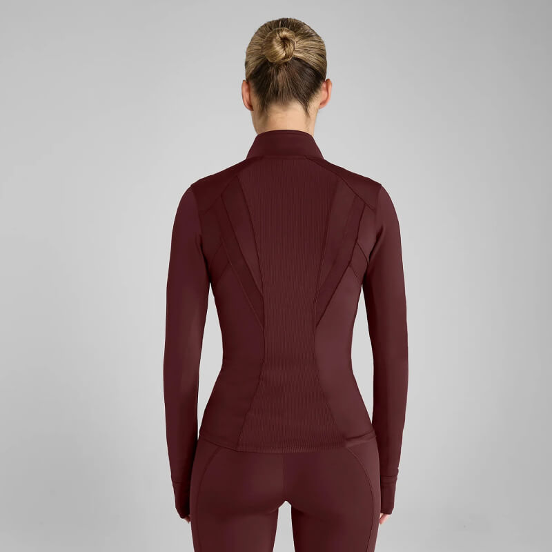 Woman in Aztec Diamond Core Fitted Jacket Cherry, seen from behind, on gray background.