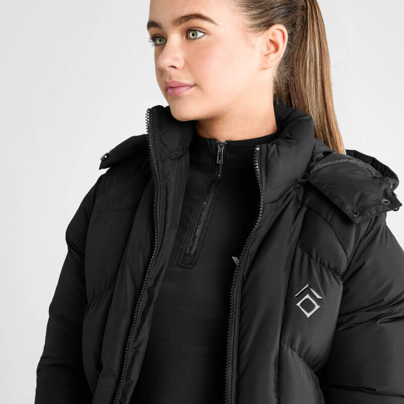 Young woman in Aztec Diamond Young Rider Long Puffer Jacket Black, facing right, plain background.