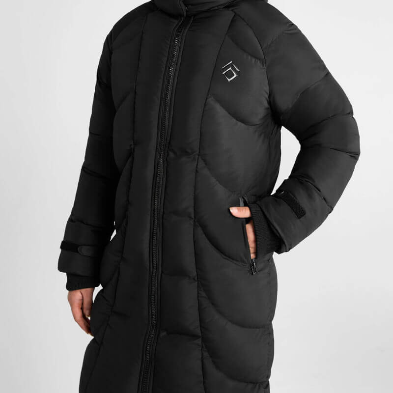 Aztec Diamond Young Rider Long Puffer Jacket in black, model with hands in zip pockets.