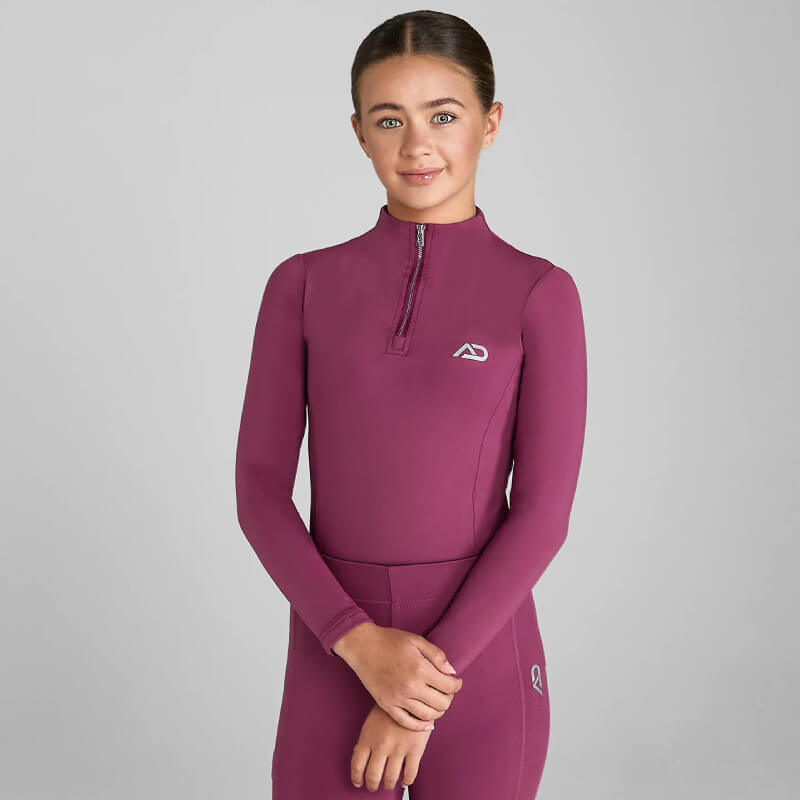 A young woman wears the Aztec Diamond YR Baselayer Raspberry against a plain grey background.