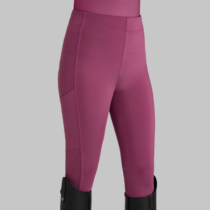 Wearing Aztec Diamond YR Full Seat Leggings Raspberry with black boots on a gray background.