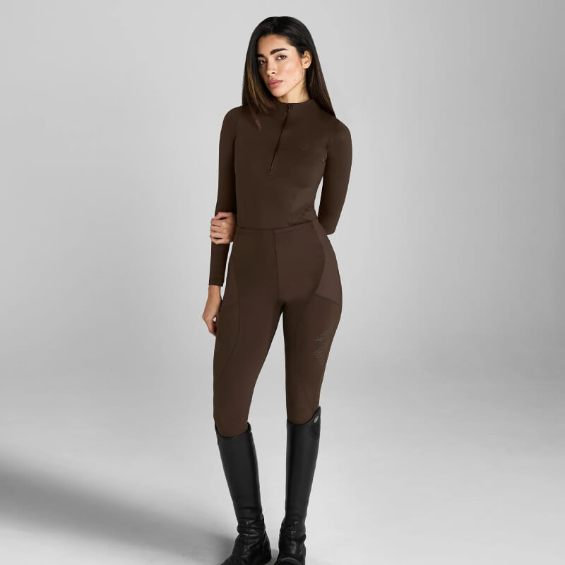 Woman in Aztec Diamond Core Baselayer Mocha and black boots stands in studio with gray background.