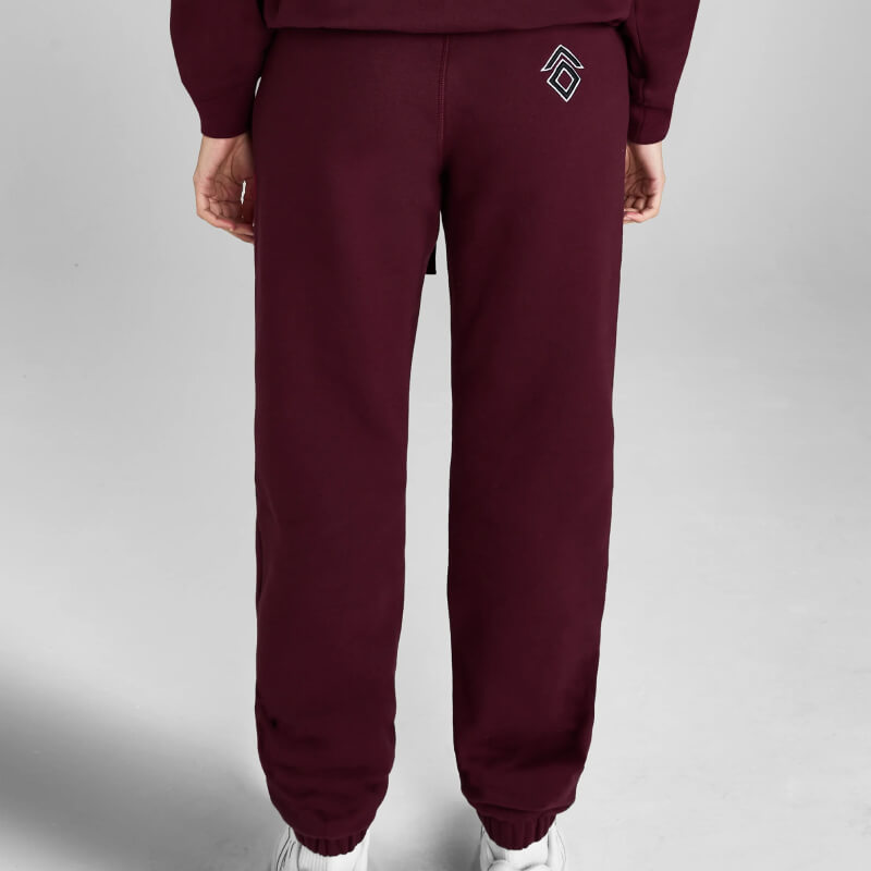 Wearing Aztec Diamond EQ Club Sweatpants Cherry with a white geometric logo on the pocket.
