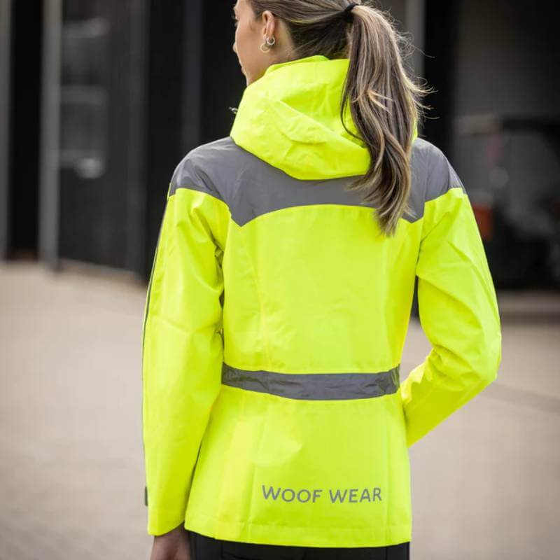 Person wearing Woof Wear All Season Waterproof Riding Jacket Hi Vis Yellow, standing outdoors.