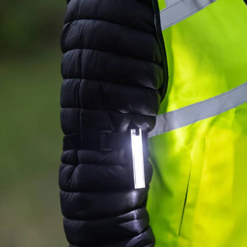 Woman in safety gear wears Woof Wear LED 3-in-1 Rider Safety Lights and a high-vis vest.