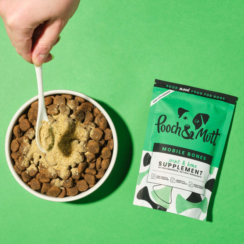 Pooch & Mutt Mobile Bones 200g joint supplement sprinkled on kibble, green background.