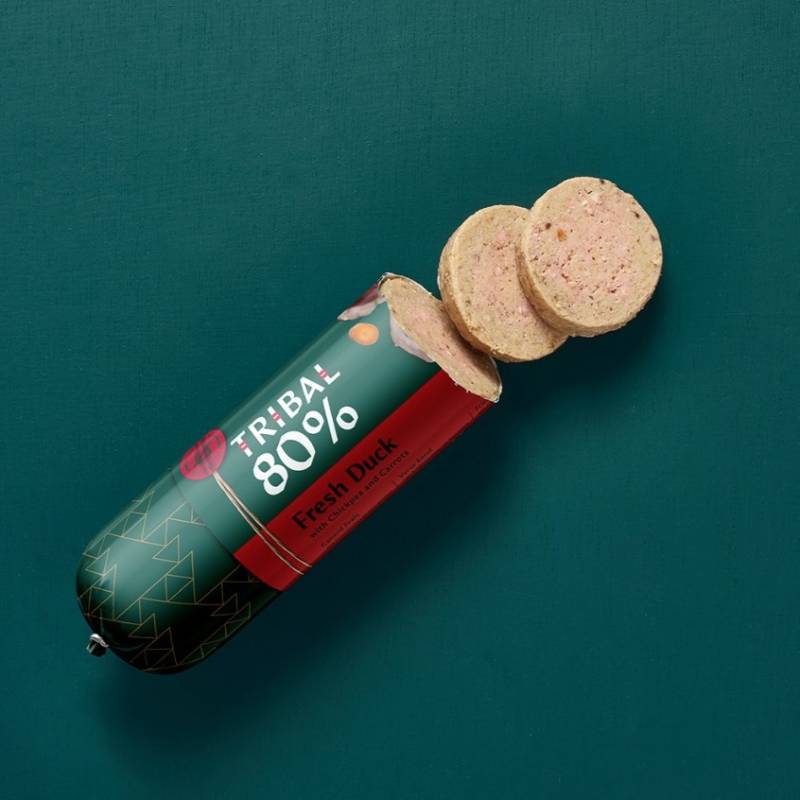 Tribal 80% Dog Sausage 300g, with three slices, on a green background.