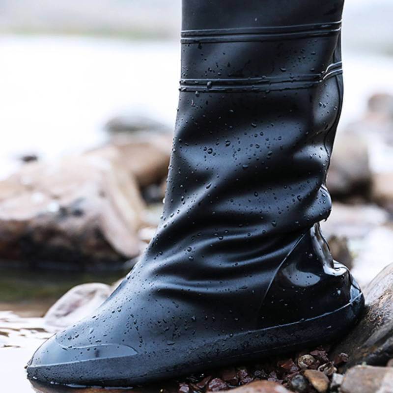 Person wears black silicone Reinwear rain boots over gray pants, labeled Reinboots Black.