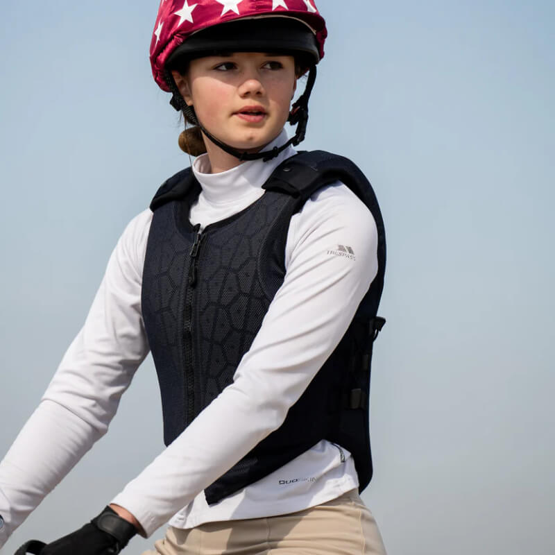 Young rider in a Racesafe HX3 Young Rider Body Protector Black and helmet, outdoors.