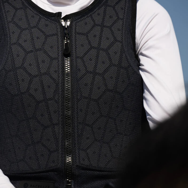 Young rider wears a Racesafe HX3 Young Rider Body Protector Black over a white shirt.