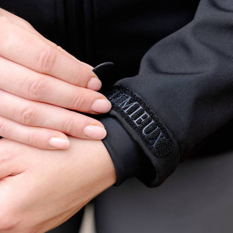 Hands adjusting the cuff of a LeMieux Celine Soft Shell Jacket Black, a lightweight jacket.