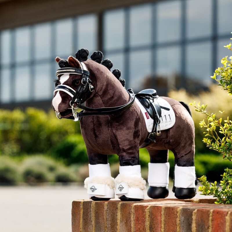LeMieux Toy Pony Dressage Square White by LeMieux stands outdoors with bridle and saddle.
