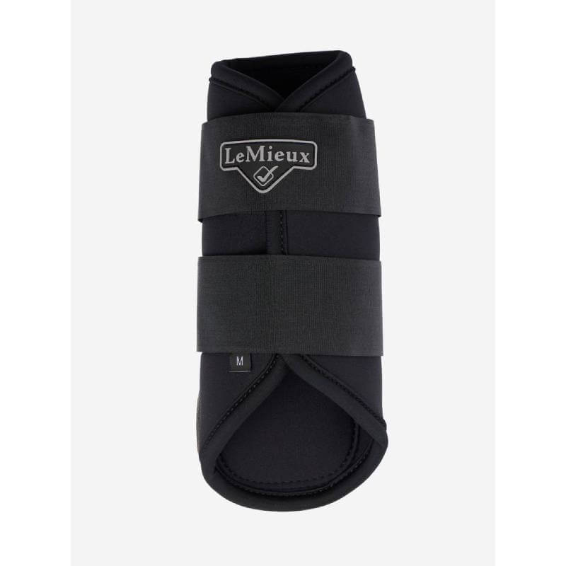 A horse in LeMieux Grafter Brushing Boots Black stands on gravel.