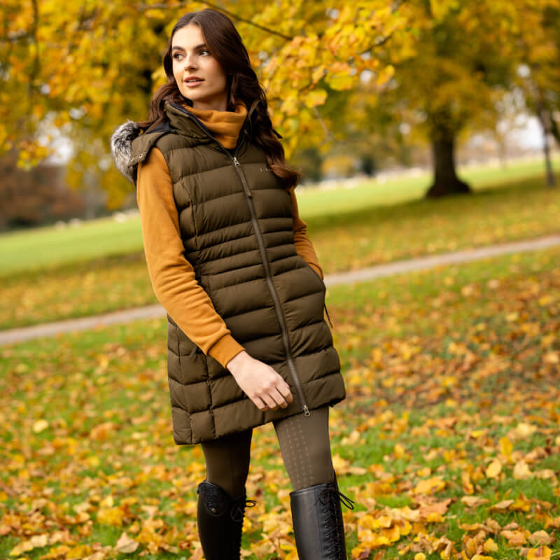 Woman in the LeMieux Harper Longline Puffer Gilet Alpine, enjoying autumn leaves.