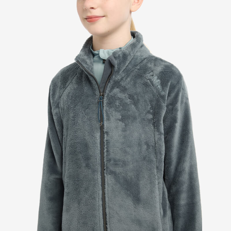 Girl in a petrol LeMieux Young Rider Libby Fleece, standing against a plain background.
