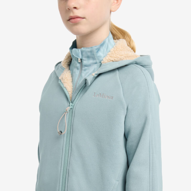 Young girl in a LeMieux Young Rider Hollie Lined Hoodie Glacier, facing slightly left.