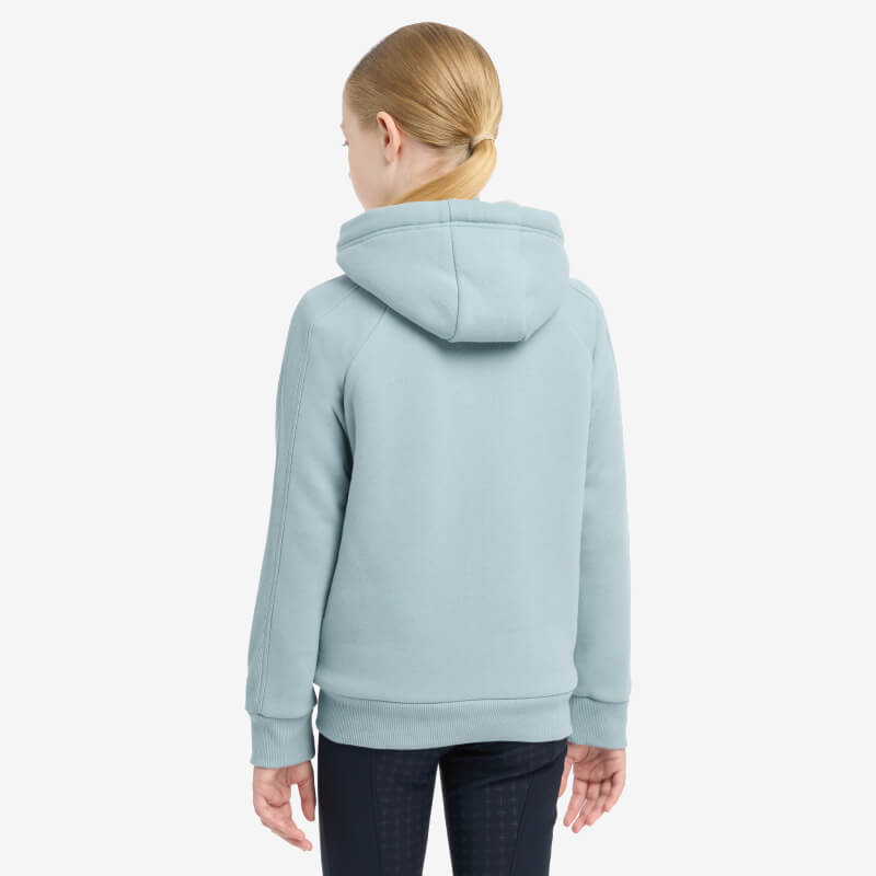Girl with blonde hair in LeMieux Young Rider Hollie Lined Hoodie Glacier, shown from the back.