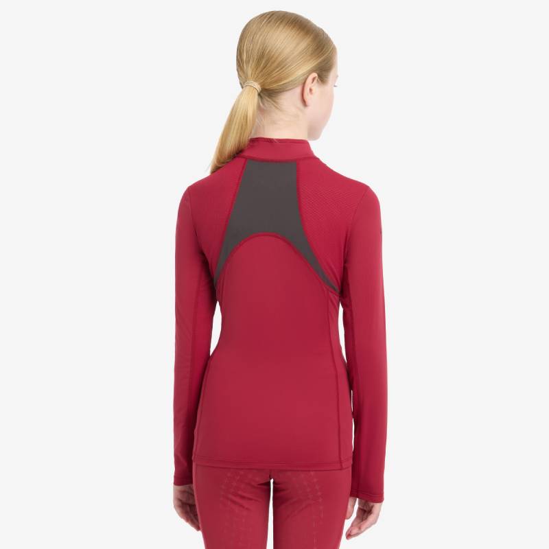 Girl in LeMieux Mia Mesh Baselayer Ember, standing and smiling in matching activewear ensemble.