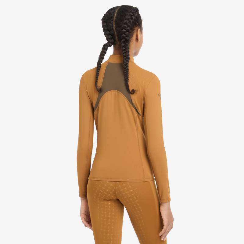 Teen girl in LeMieux Young Rider Mia Mesh Baselayer Ginger, smiling against a white background.