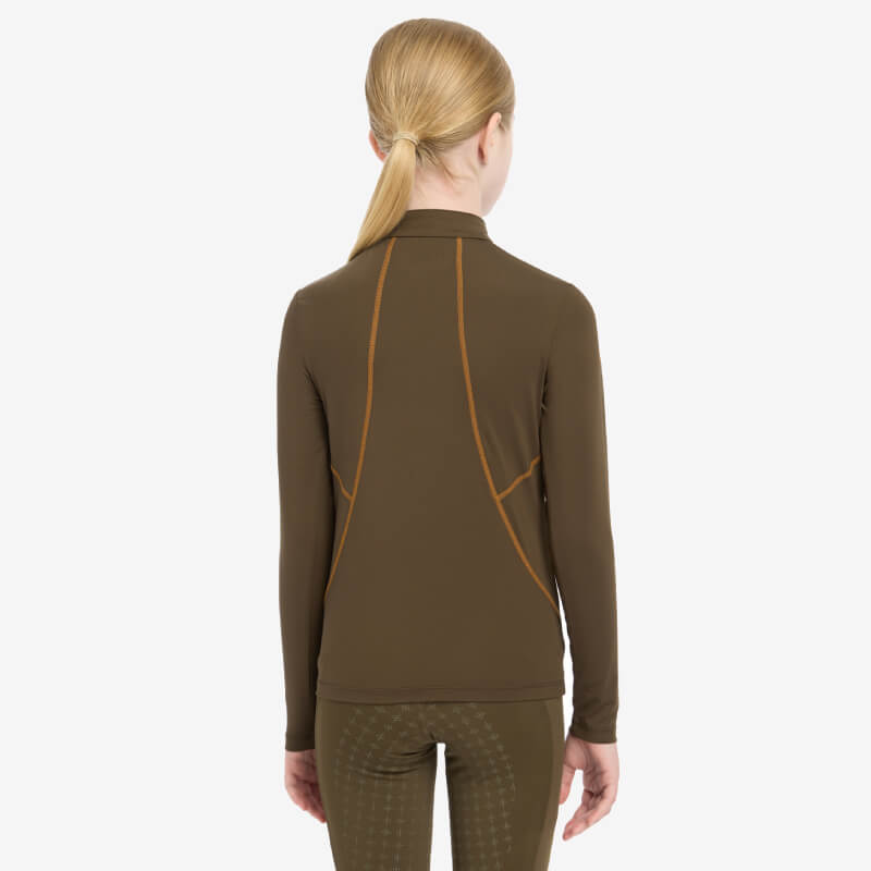 Young rider in blonde ponytail wears LeMieux Young Rider Baselayer Alpine, back view.