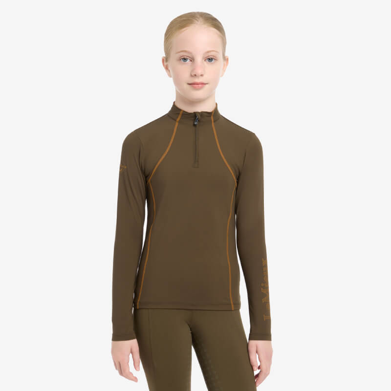 Young girl in a LeMieux Young Rider Baselayer Alpine, standing against a white background.