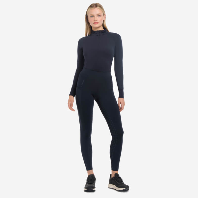 Person wearing LeMieux Naomi Pull On Breech Navy Full Seat and black sneakers, white background.