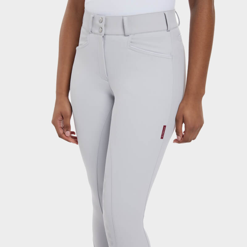 Wearing LeMieux Imogen Knee Grip Breech Light Grey and a white top, shown mid-torso to knees.