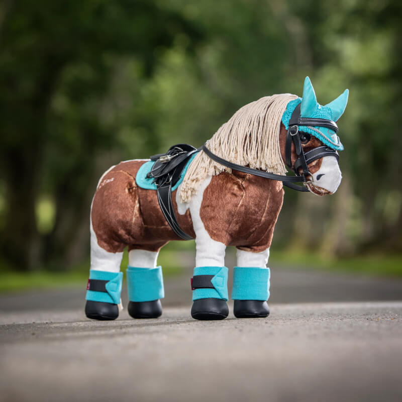 LeMieux Toy Pony Pad Azure by LeMieux stands on a road lined with green trees.