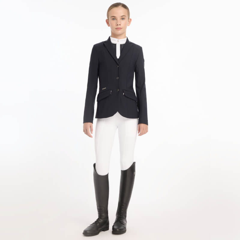 Person in a Lemieux Young Rider Kennedy Show Jacket Navy, white breeches, and tall black boots.