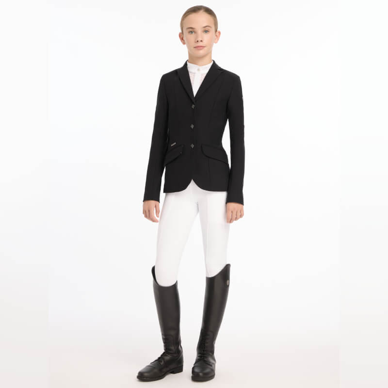A young rider in a LeMieux Kennedy Show Jacket Black, white pants, and tall black boots.