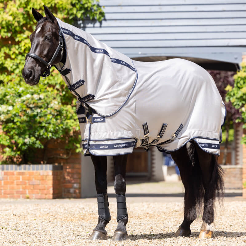 Black horse outdoors in LeMieux Arika Armour-Tek Fly Rug Grey with navy trim for UV protection.