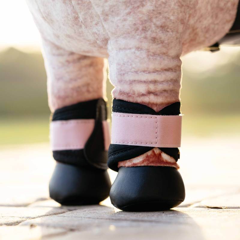 A close-up of legs wearing LeMieux Toy Pony Grafter Boots Blossom outdoors.