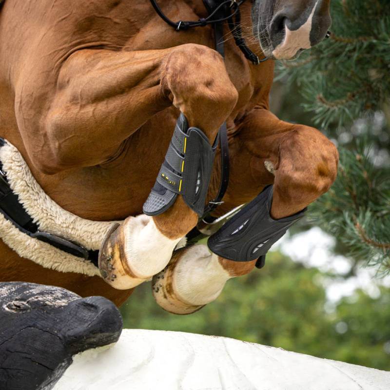 Close-up of a horse jumping, wearing LeMieux MIMSafe Boot Front Black for shock absorption.