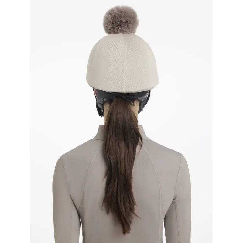 Person with long brown hair wears a LeMieux Maria Mesh Hat Silk Almond helmet cover, seen from behind.